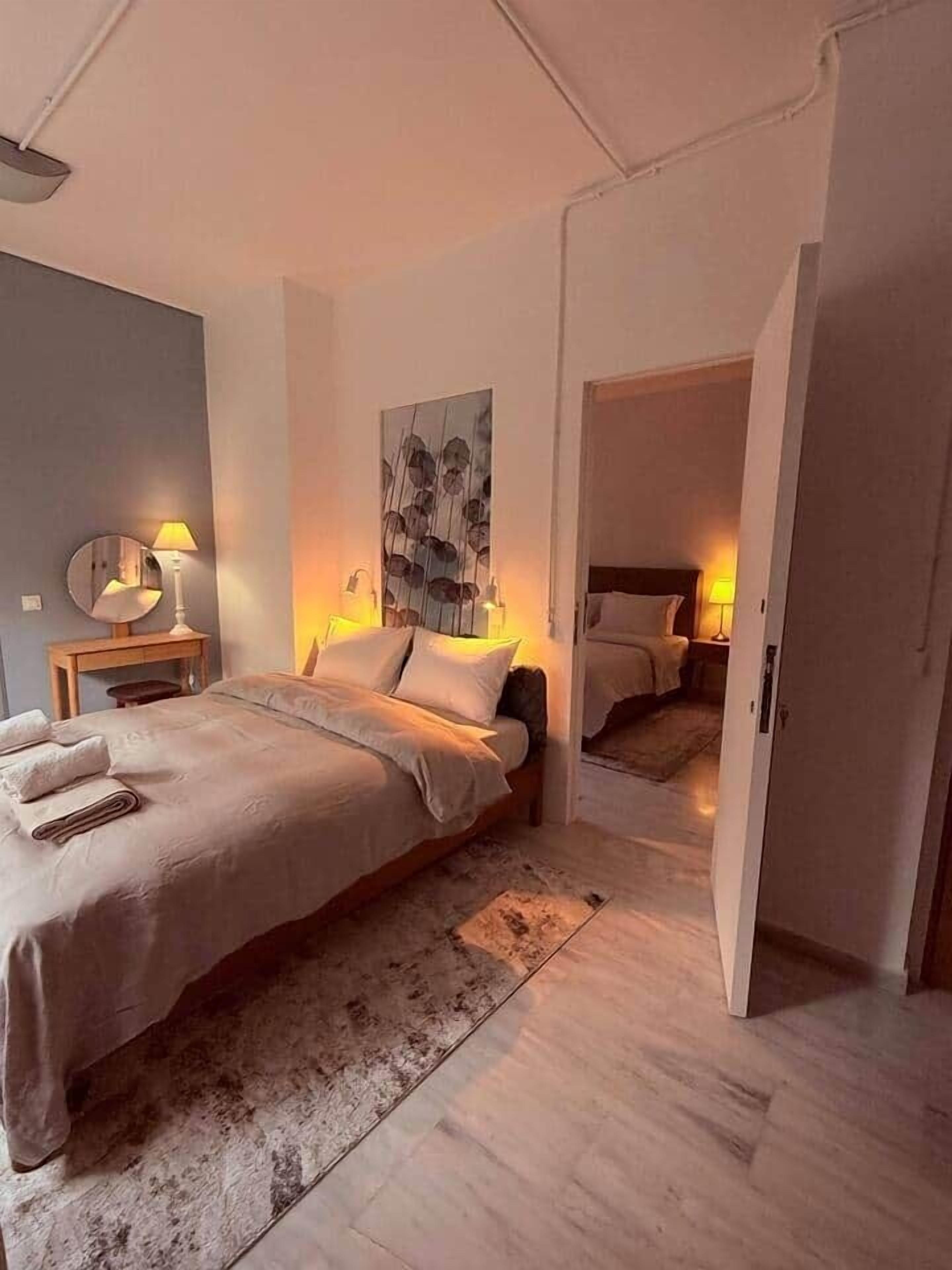 A modern bedroom with a large bed, bedside lamps, a rug, and a painting on the wall.