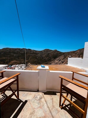 A terrace with a view of a mountainous landscape, a white wall, and two wooden chairs. - Archontiko Serifos (Syros)