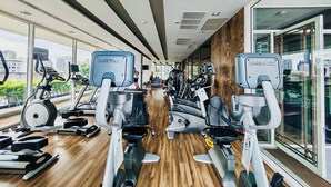 A modern gym with various cardio machines, wooden flooring, and large windows offering city views. - Downtown, Cozy 48sqm 1BR, middle of Thonglor, High Floor, Fast 500mpbs Wifi (Krung Thep Maha Nakhon)