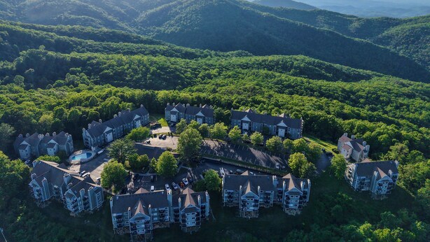 An aerial view of a residential area with multiple houses surrounded by lush greenery and hills in the background. - Romantic Smoky Mountain Escape-Hot tub-Pool-fireplace (Gatlinburg)