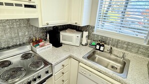 A kitchen with white cabinets, a stainless steel stove, a microwave, and a sink. - Romantic Smoky Mountain Escape-Hot tub-Pool-fireplace (Gatlinburg)