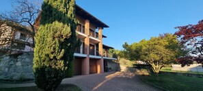 A multi-story building with a brick facade, a balcony on the second floor, and a paved driveway leading to the entrance. - Detached family home in Piverone, near Lake Viverone (Piverone)