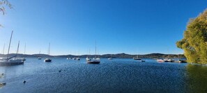 Un llac tranquil amb diversos velers amarrats, envoltat de turons i un cel serè.