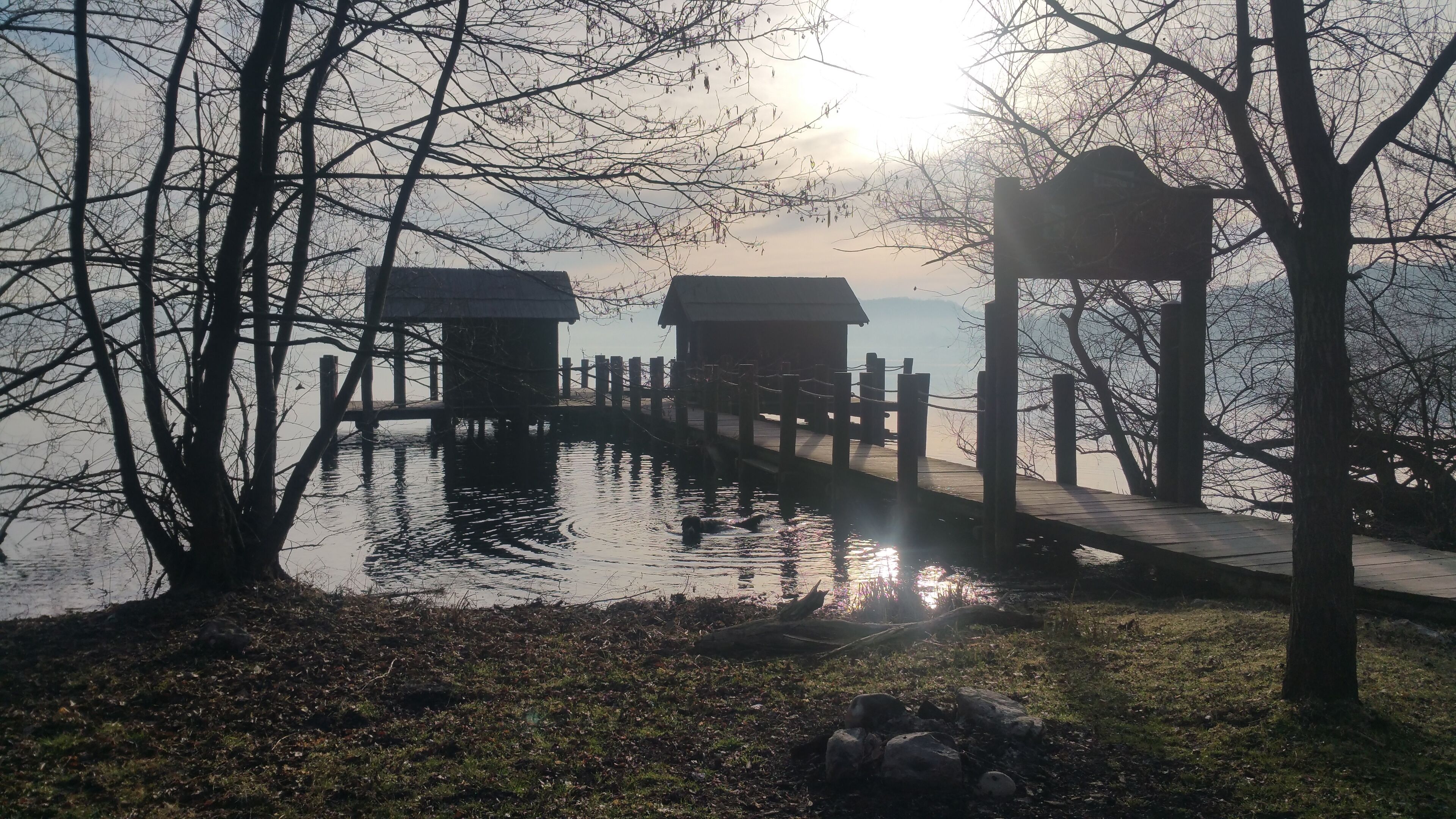A wooden pier leading to two small wooden structures by a calm body of water.