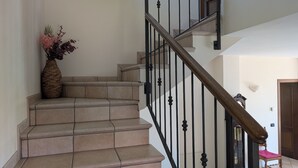 A staircase with beige tiles, black balusters, and a wooden handrail. - Detached family home in Piverone, near Lake Viverone (Piverone)