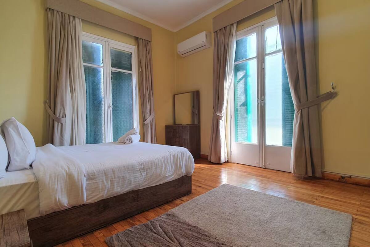 Une chambre à coucher avec un lit, une commode et une fenêtre avec des rideaux.