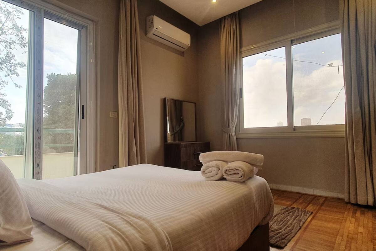 Une chambre d’hôtel avec un lit, une fenêtre avec des rideaux, un appareil de climatisation et une vue sur l’extérieur.