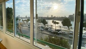 Vista desde una ventana sobre un estacionamiento y un río, con edificios al fondo.