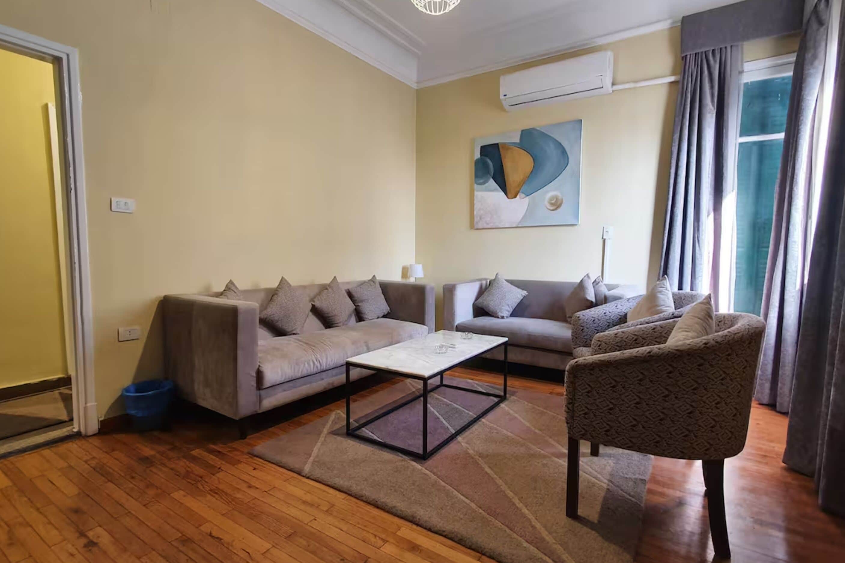 A living room with two sofas, a coffee table, and a patterned armchair.