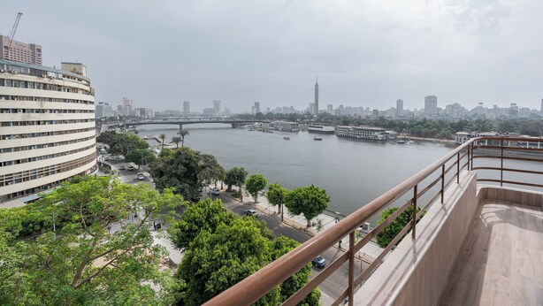 Un edificio alto con un río y el horizonte de la ciudad al fondo.