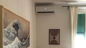 A room with a traditional Japanese wave painting, an air conditioning unit, a chair, and a window with curtains. - Casajeanmarc in Moneglia, a picturesque Ligurian town a stone's throw from the 5 Terre (Moneglia)