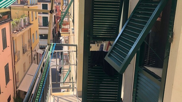 A balcony with a metal railing, a green awning, and a view of adjacent buildings. - Casajeanmarc in Moneglia, a picturesque Ligurian town a stone's throw from the 5 Terre (Moneglia)