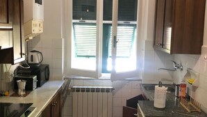 A compact kitchen with a window, a radiator, and basic appliances. - Casajeanmarc in Moneglia, a picturesque Ligurian town a stone's throw from the 5 Terre (Moneglia)
