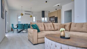 Un soggiorno moderno con un divano angolare beige, un tavolino rotondo e poltrone color acquamarina.