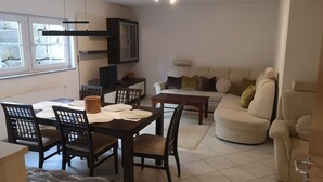 Een moderne woonkamer met een eethoek, een bank en een televisie.