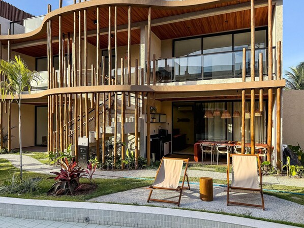 A modern building with a curved facade, large windows, and a balcony with wooden railings. - Naay Villas Boutique (Porto de Pedras)