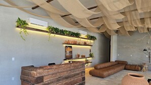 A modern interior with a stone floor, a wooden bench, a sofa, and a terracotta pot.
