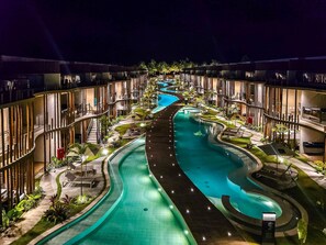 A modern hotel with a central swimming pool, multiple balconies, and outdoor seating areas. - Naay Villas Boutique (Porto de Pedras)