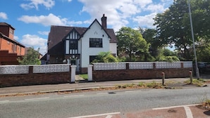 A two-story building with a white facade and dark roof, surrounded by a white fence with a lattice pattern. - Room 1 Cottage   White House Old Trafford  Manchester (Stretford)