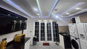 A compact kitchen with a built-in microwave, a washing machine, and a refrigerator. - Room 1 Cottage   White House Old Trafford  Manchester (Stretford)