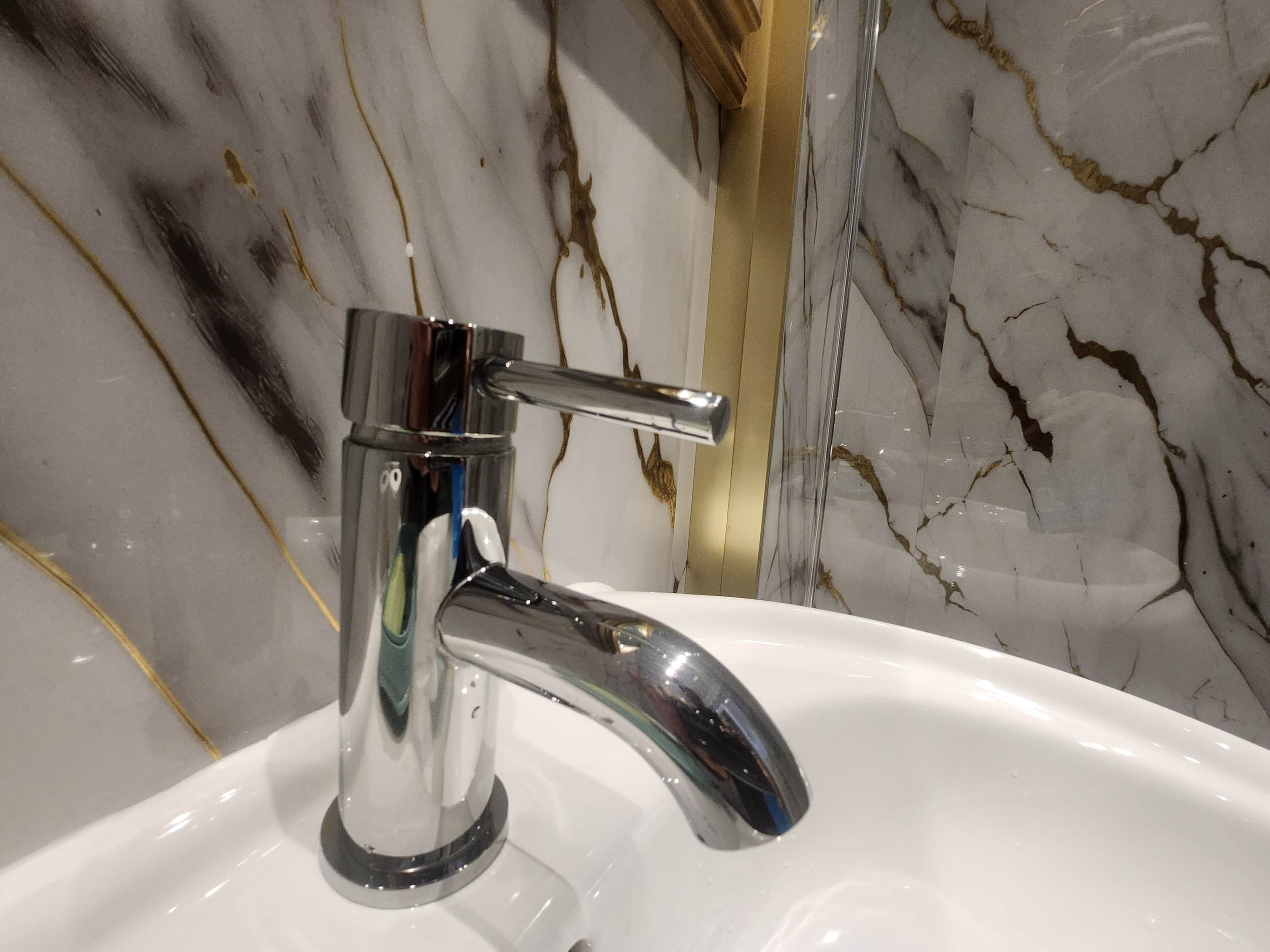 Un lavamanos moderno con grifo de cromo y una salpicadura de mármol.