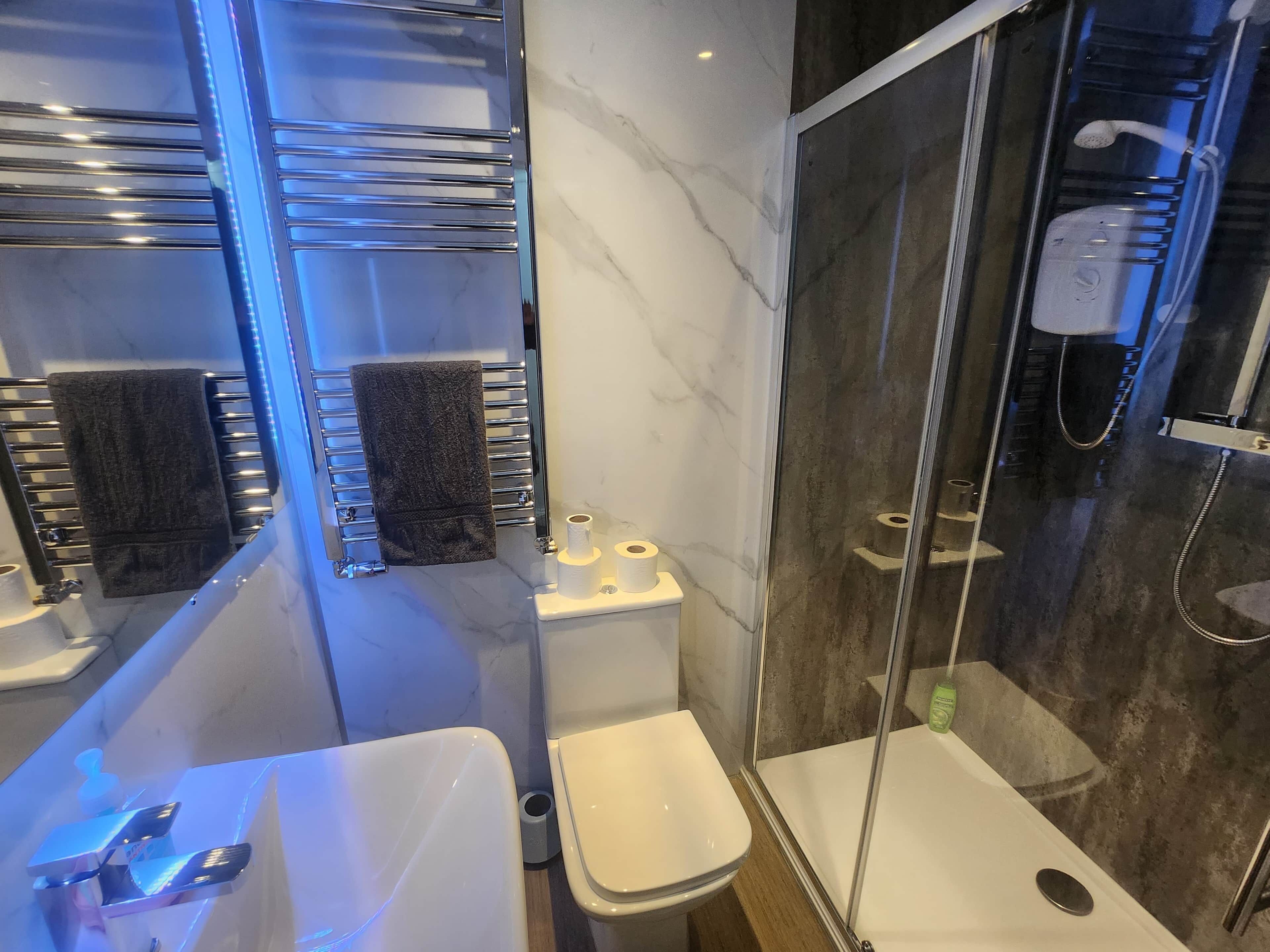 Een moderne badkamer met een douchecabine van glas, een wastafel met spiegel en een toilet.