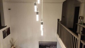 Eine Treppe mit Geländer, einer Hängelampe und einem gerahmten Bild an der Wand.