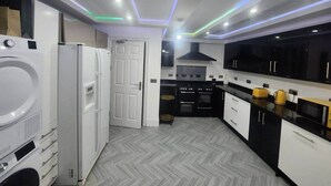 Een moderne keuken met witte apparaten, zwarte kasten en een visgraatvloer.