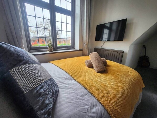 A hotel room with a bed, a window, a flat-screen TV, and a guitar. - Room 4 Cottage  White House Manchester (Stretford)