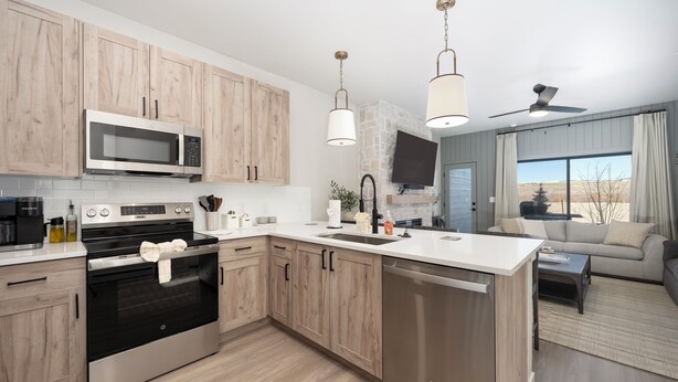 Uma cozinha moderna com armários de madeira, eletrodomésticos de aço inoxidável e uma grande janela com vista para o exterior.