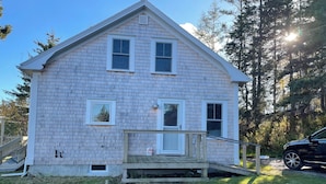 A two-story house with a front porch, a small deck, and a garage.
