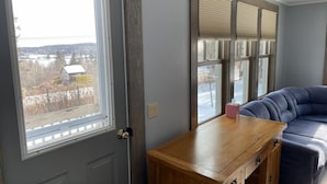 A room with a door, a window with blinds, a blue sofa, and a wooden table.