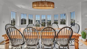 A dining area with a round table, black chairs, and a wooden ceiling light. - 7-bedroom water view compound featuring a main house and annex. (Southport)