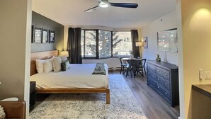 A bedroom with a bed, a desk, and a chair. There is a window with curtains and a ceiling fan. - Studio near Crested Butte slopes, pool & hot tub (Crested Butte)