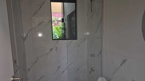 A bathroom with a marble floor, a toilet, a sink, and a shower. - Edificio Navarra (Asunción)