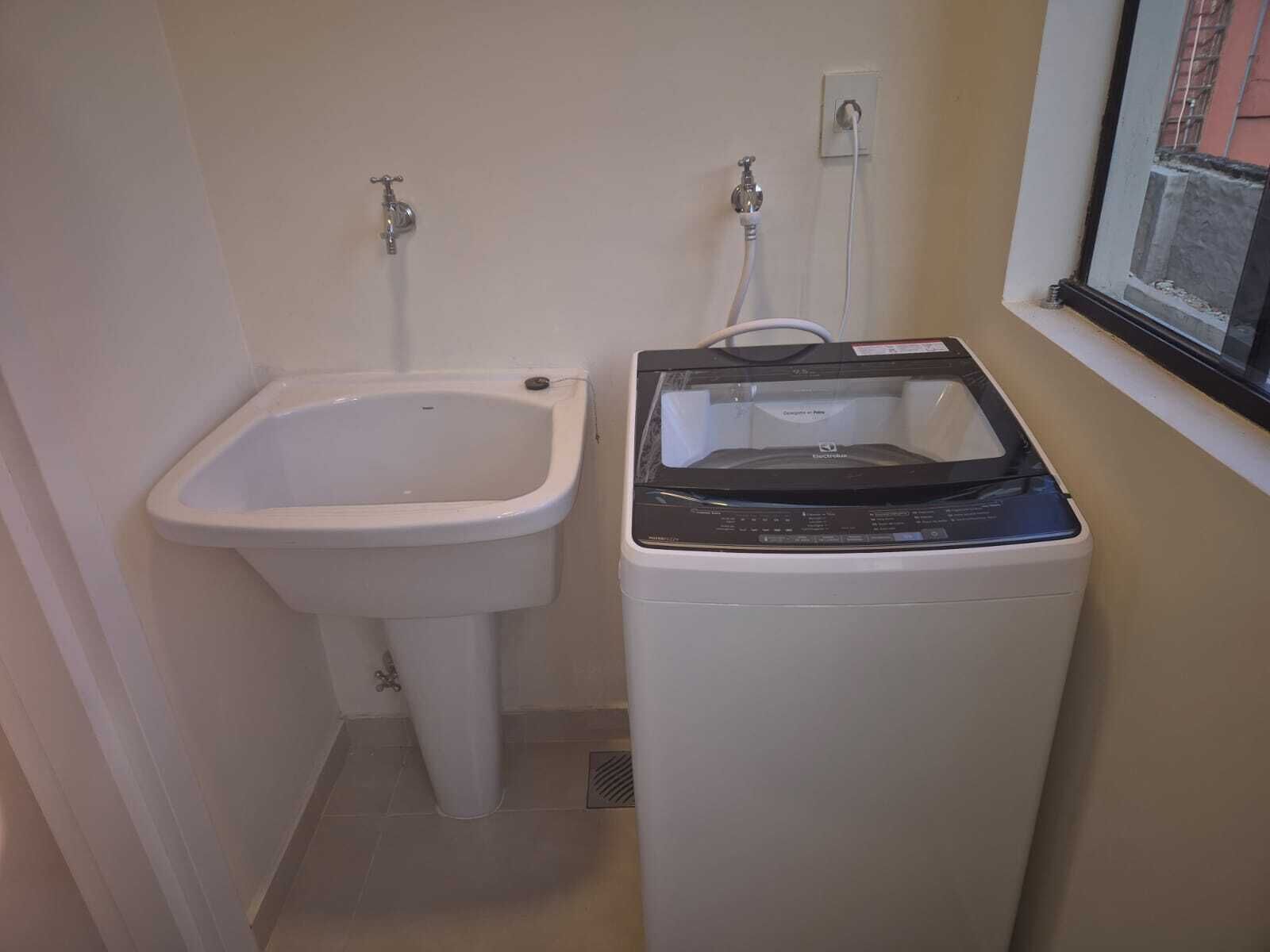 A small bathroom with a pedestal sink and a front-loading washing machine.