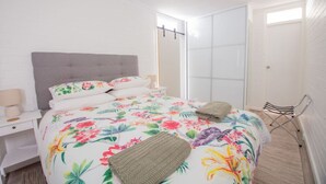 Een slaapkamer met een bed, een nachtkastje, een stoel en een schuifdeurkast.