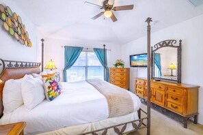 A bedroom with a four-poster bed, a wooden dresser, a ceiling fan, and a large mirror. - Family Resort Home w Pool, BBQ & Game Room (Davenport)