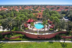 A resort with a central pool, surrounded by palm trees and red-roofed buildings. - Family Resort Home w Pool, BBQ & Game Room (Davenport)