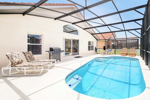 A covered outdoor swimming pool with lounge chairs, a barbecue grill, and a patio area. - Family Resort Home w Pool, BBQ & Game Room (Davenport)