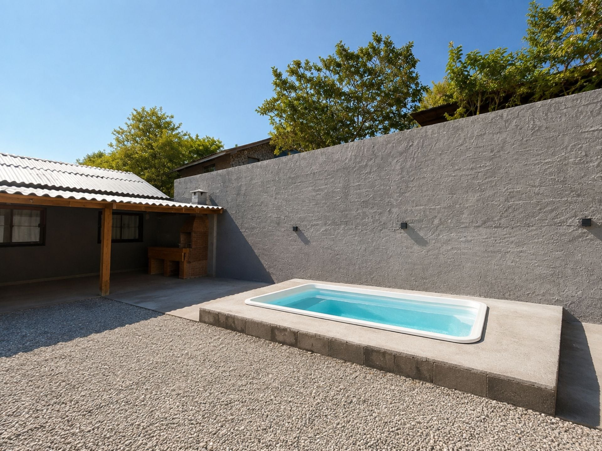 A swimming pool with a stone wall and a covered patio area.