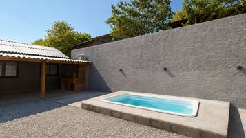 A swimming pool with a stone wall and a covered patio area.