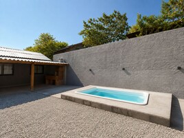 Una piscina con un muro de piedra y un patio cubierto.
