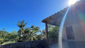 A covered outdoor area with a concrete wall, a wooden pergola, and a building with a window. - Refúgio Menegaz - Governador Celso Ramos - SC (Governador Celso Ramos)