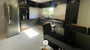 A modern kitchen with stainless steel appliances, a black countertop, and a window providing natural light. - Refúgio Menegaz - Governador Celso Ramos - SC (Governador Celso Ramos)