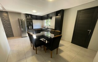 Cocina moderna con comedor, con una decoración en blanco y negro, un refrigerador, horno y una puerta negra.