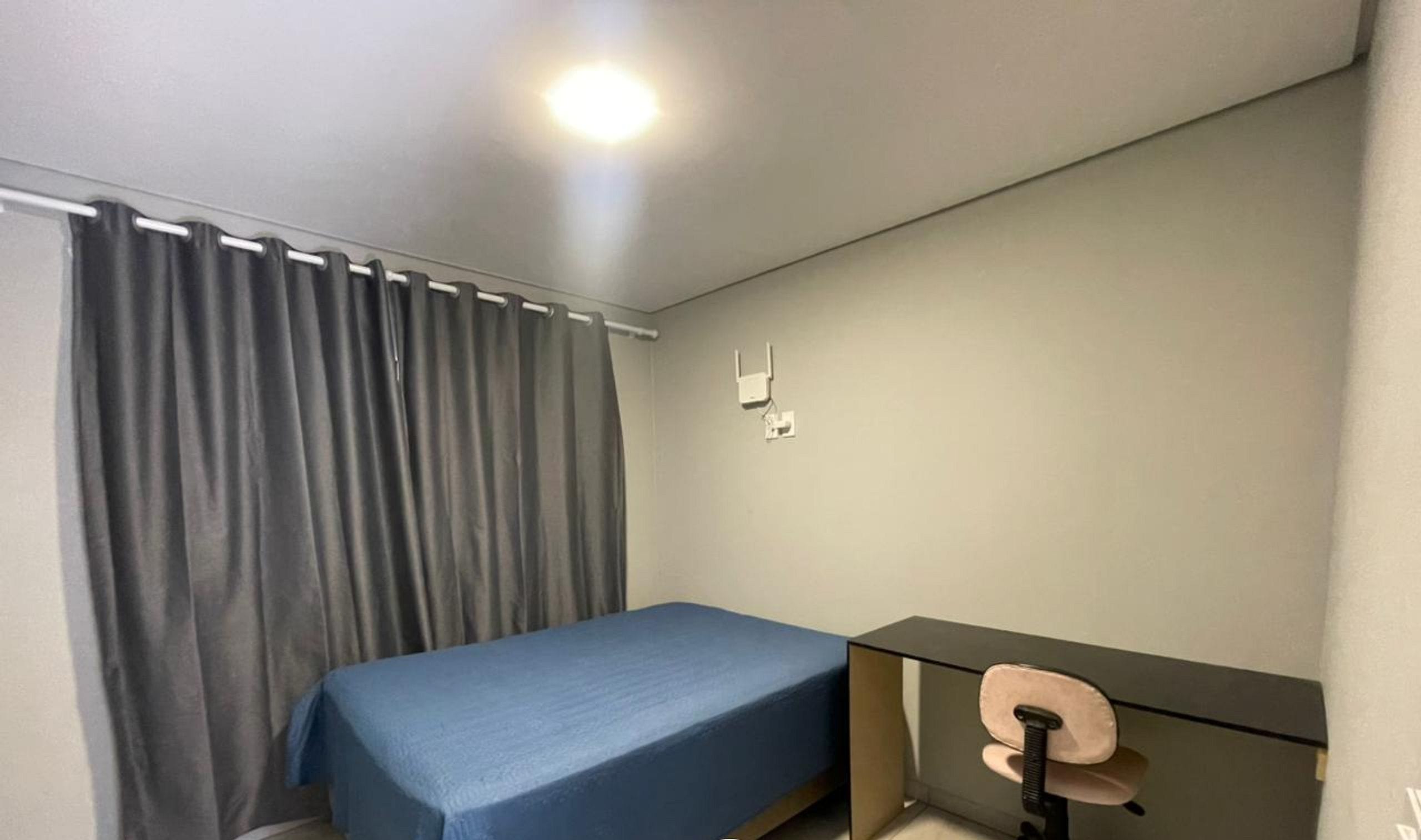 A bedroom with a single bed, a desk, and a chair.