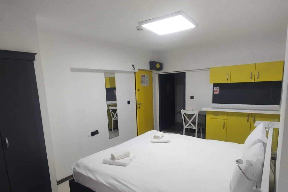 A hotel room with a bed, a desk, and a kitchenette.