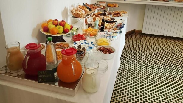 Un bufé con diversas frutas, pasteles y bebidas.