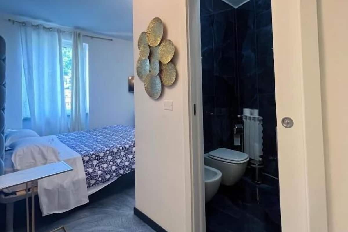 A bedroom with a bed, a desk, and a bathroom visible through an open door.